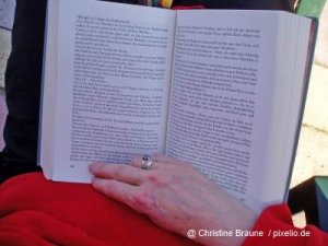 Rückansicht einer älteren Frau die ein Buch liest