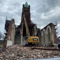 Bild einer Kirche, die von einem Bagger abgerissen wird